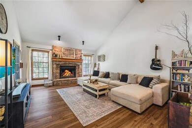 Living room with dark wood-type flooring, plenty of natural light, high vaulted ceiling, and a fireplace