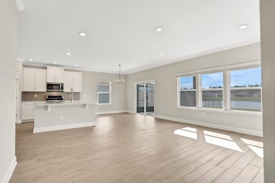 Unfurnished living room featuring a chandelier, healthy amount of natural light, recessed lighting, crown molding, and light wood-type flooring
