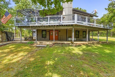 Rear view of property with a chimney, a lawn, and a wooden deck