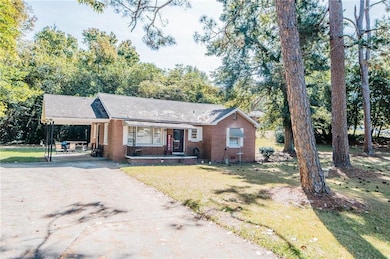 Ranch-style house with a porch, an attached carport, driveway, brick siding, and a front lawn