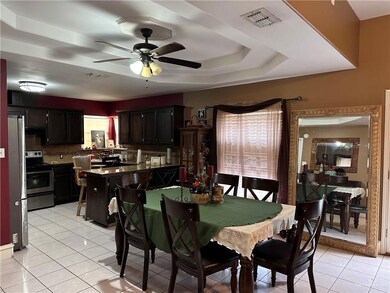 Tiled dining space with a raised ceiling and ceiling fan