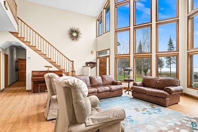 Living area with a towering ceiling, light wood-style floors, baseboards, and stairway