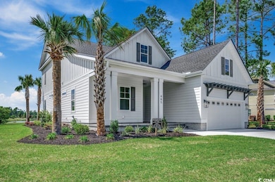 Modern farmhouse featuring board and batten siding, covered porch, a front yard, and driveway
