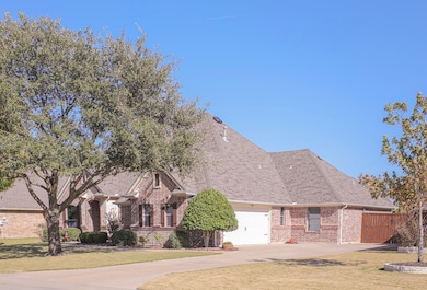 Traditional home featuring brick siding, roof with shingles, concrete driveway, and a garage