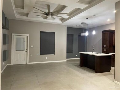 Kitchen featuring pendant lighting, sink, ceiling fan, dark brown cabinets, and a center island with sink