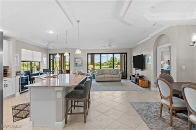 Kitchen featuring hanging light fixtures, white cabinetry, a kitchen breakfast bar, an island with sink, and light stone countertops