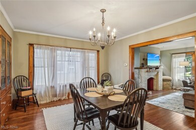 Dining area featuring an inviting chandelier, dark hardwood / wood-style flooring, a fireplace, and crown molding
