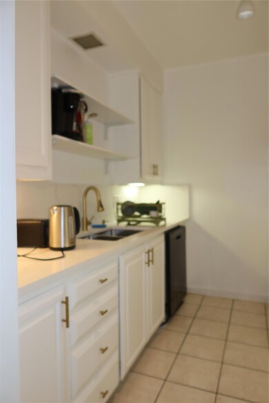 Kitchen with white cabinetry, light countertops, 