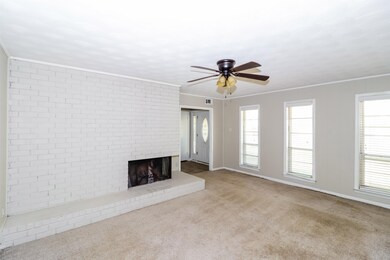 Unfurnished living room featuring crown molding, carpet flooring, a fireplace, and ceiling fan