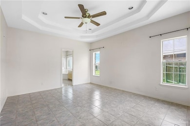 Unfurnished room with a tray ceiling, a ceiling fan, and light tile patterned flooring