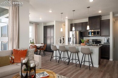Kitchen with appliances with stainless steel finishes, a breakfast bar, wood finished floors, dark brown cabinetry, and recessed lighting