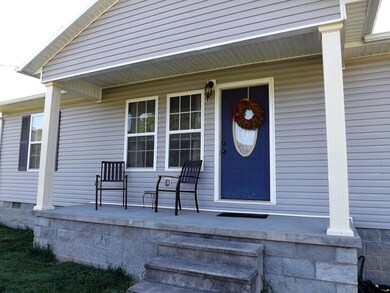Welcoming front porch with sidewalk leading to concrete parking area.