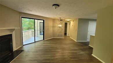 Unfurnished living room featuring a textured ceiling, dark wood-style floors, a fireplace with raised hearth, and a chandelier