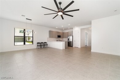 Living room with ceiling fan, light tile patterned floors, baseboards, and recessed lighting