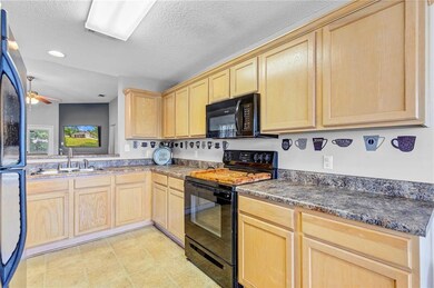 Kitchen with light brown cabinetry, a sink, dark c
