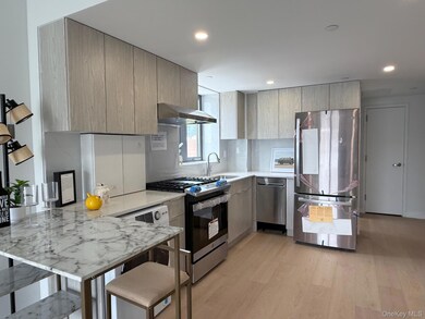 Kitchen with appliances with stainless steel finishes, wall chimney exhaust hood, modern cabinets, a peninsula, and light wood finished floors