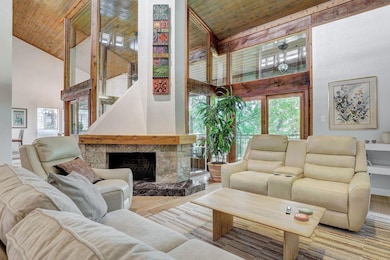 Living area featuring wood ceiling, high vaulted ceiling, a stone fireplace, and wood finished floors