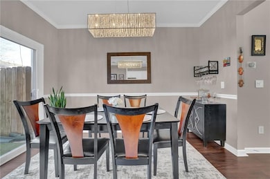 Dining room with a chandelier, wood finished floors, crown molding, and baseboards