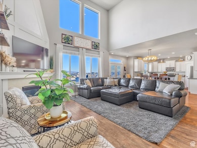 Living room with light wood-style flooring, a chandelier, a fireplace, and a high ceiling