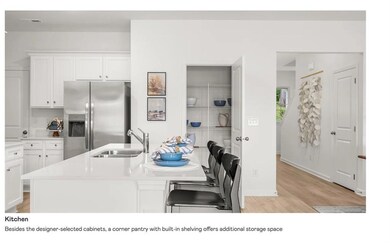 Kitchen with stainless steel fridge, white cabinets, a kitchen bar, and light wood-style floors