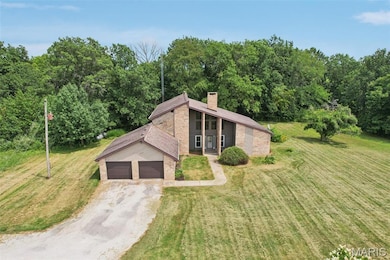 Mid-century inspired home featuring a front lawn, a chimney, dirt driveway, an attached garage, and brick siding