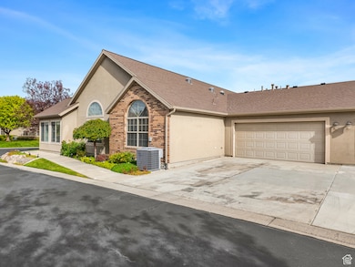 Ranch-style home with stucco siding, driveway, brick siding, and an attached garage