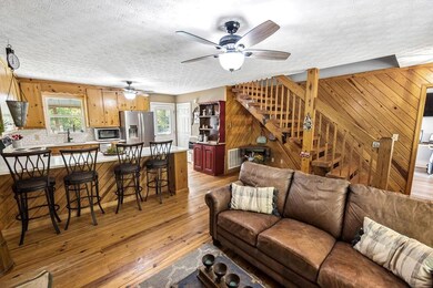 Living room featuring a ceiling fan, light wood-st