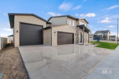 Contemporary home featuring stone siding, driveway, an attached garage, and stucco siding