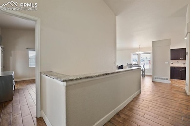 Hall with wood finished floors, a chandelier, lofted ceiling, and baseboards