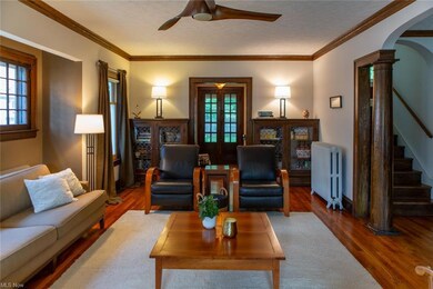 Living room with light hardwood flooring, radiator, crown molding, and french doors