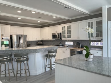 Kitchen featuring white cabinets, glass insert cabinets, decorative backsplash, appliances with stainless steel finishes, and recessed lighting