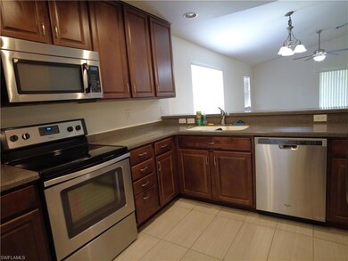 Kitchen featuring light tile patterned flooring, ceiling fan, hanging light fixtures, appliances with stainless steel finishes, and sink