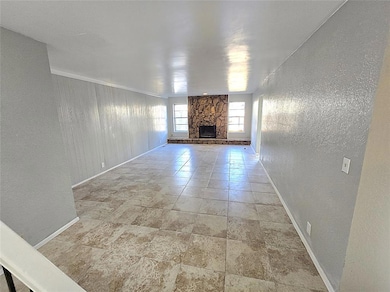 Unfurnished living room with a textured wall and a stone fireplace