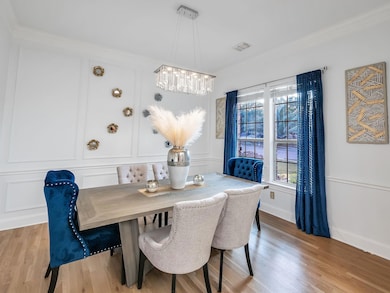 Dining area featuring a notable chandelier, crown molding, and light wood-type flooring