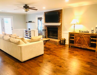 Living room featuring ceiling fan, brick wall, har