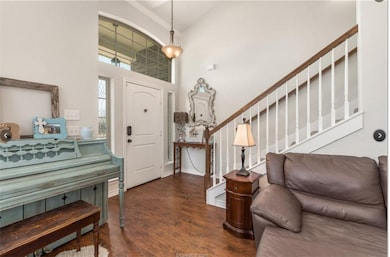 Foyer entrance featuring dark wood-style flooring, stairway, and a high ceiling