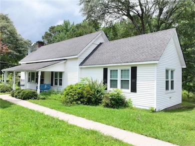 View of front of property featuring a shingled roof, a porch, and a front lawn