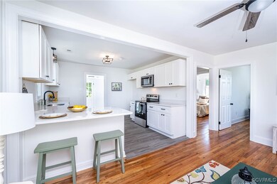 Kitchen with white cabinets, light countertops, stainless steel appliances, and light hardwood flooring