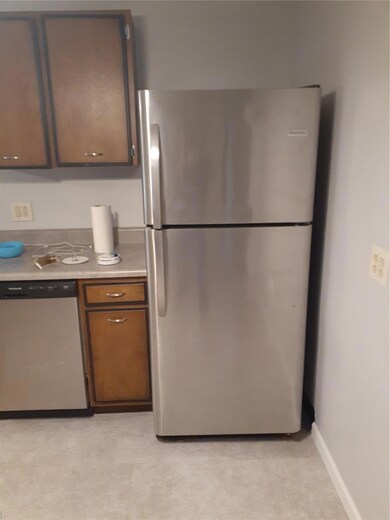 Kitchen featuring baseboards, light countertops, dishwasher, and freestanding refrigerator