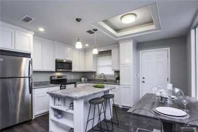 Spare room featuring a tray ceiling, wood finished floors, a ceiling fan, and baseboards