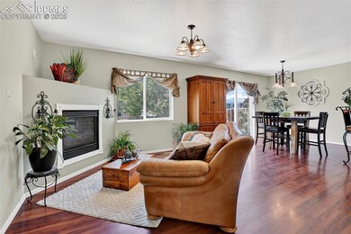 Living room with a chandelier, dark wood finished floors, and a gas fireplace