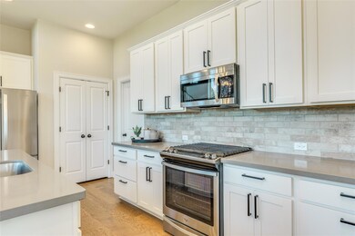 Kitchen with white cabinets, light countertops, a