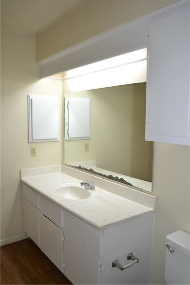 Half bathroom featuring vanity, toilet, and wood f