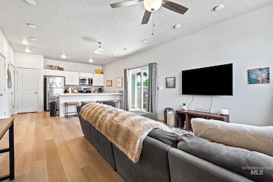 Living room with light wood-type flooring, a textured ceiling, and ceiling fan