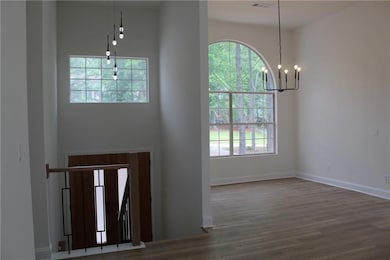 Entrance foyer with a chandelier, plenty of natural light, wood finished floors, and baseboards
