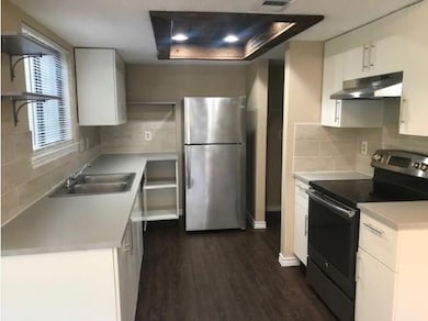 Kitchen featuring appliances with stainless steel finishes, light countertops, tasteful backsplash, and white cabinets