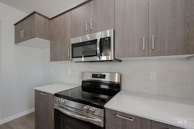 Kitchen featuring stainless steel appliances, modern cabinets, tasteful backsplash, and light wood-style flooring