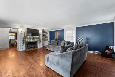 Living room with original historic lighting and brick fireplace (gas), pristine crown molding, original hard wood flooring, and built in decorative shelves for storage!