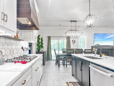 Kitchen featuring appliances with stainless steel finishes, custom range hood, a sink, a chandelier, and light countertops