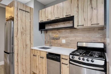 Kitchen with light brown cabinets, appliances with stainless steel finishes, tasteful backsplash, open shelves, and modern cabinets